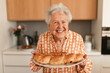 Happy senior woman with homemade sweet braided bread with raisins.
