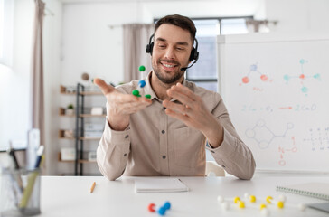 distance education, school and remote job concept - happy smiling male chemistry teacher in headset with molecular model having online class at home office