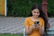 Young Indian girl smiling using mobile phone in the outdoor