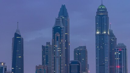 Wall Mural - Modern skyscrapers in Dubai city night to day transition timelapse from the Palm Jumeirah Island. Dubai, United Arab Emirates. Dubai marina and JBR in clouds at early morning