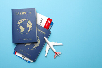 Sticker - International passports, boarding passes and airplane model on light blue background, flat lay. Space for text