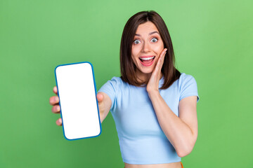 Wall Mural - portrait of astonished cheerful girl hand touch cheek showing empty space telephone screen isolated 