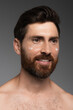 © LIGHTFIELD STUDIOS - portrait of bearded man with cream on face smiling isolated on grey.