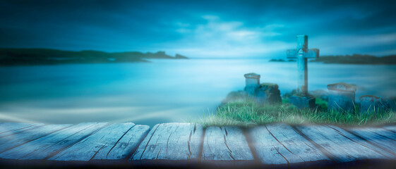 Wall Mural - a spooky nighttime background scene of a misty sky and sea with gravestones and rustic wooden bench 