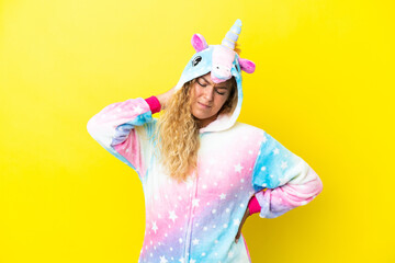 Wall Mural - Girl with curly hair wearing a unicorn pajama isolated on yellow background with neckache