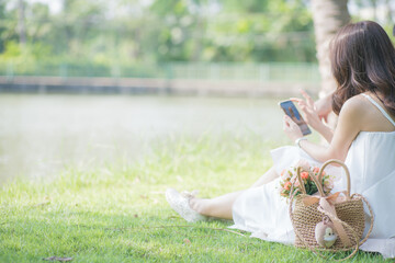 Beautiful asian women use smartphone in city green park outdoor recreation relax in city park