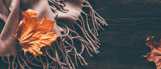Fotomurales - Autumn home cozy composition with a scarf and maple leaves on a wooden background.
