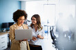 Leinwandbild Motiv Happy multiethnic business women working together online on a laptop in corporate office.