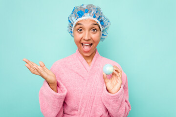 Wall Mural - Young hispanic woman holding bathtub ball isolated on blue background surprised and shocked.