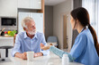© kunchainub - happy senior retire adult take a pill or drug for treatment by young female doctor from clinic hospital to takecare for health at home