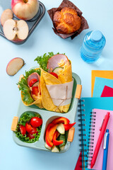 Wall Mural - School lunch box for kids with sandwich, vegetables, water and stationery on table. Healthy eating habits concept. Back to school concept