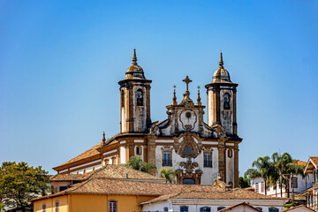 Wall Mural - Baroque style historic church tower emerging from behind old houses in Ouro Preto city in Minas Gerais state, Brazil