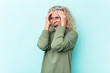 © Asier - Middle age caucasian woman isolated on blue background covering ears with hands trying not to hear too loud sound.