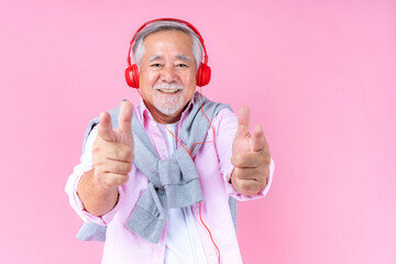 Wall Mural - senior old man smile wearing red headphones, happiness asian old man listen music dance pink background.