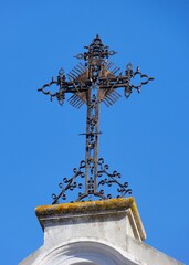 Historic metal cross in front of blue sky in Spain 