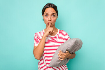 Wall Mural - Young hispanic woman holding a cushion isolated on white background keeping a secret or asking for silence.