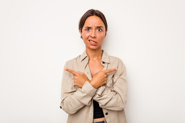 Wall Mural - Young hispanic woman isolated on white background points sideways, is trying to choose between two options.