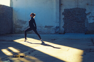 Wall Mural - Ballerina jumping and dancing in a dusty abandoned building on a sunny day