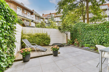 Neat paved patio with sitting area and small garden near wooden fence