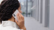 © Yuliia - Back view unrecognizable boss manager businesswoman with curly hair lady in formal shirt standing outdoors talking mobile phone call remote chatting business conversation negotiation with colleagues