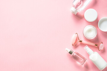 Poster - Skin care product, cream, soap serum, jade roller. Natural cosmetics on pink. Flat lay image with copy space.