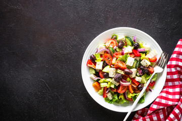 Canvas Print - Greek salad. Vegetable salad with tomato, cucumber, feta cheese and olive oil. Top view on black stone table.