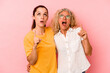 © Asier - Caucasian mom and daughter isolated on pink background pointing upside with opened mouth.