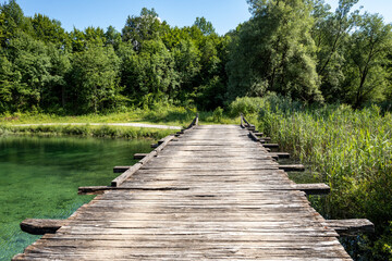 Canvas Print - Old, wooden bridge passing over beautiful Korana river flowing directly from Plitvice national park lakes, Croatia