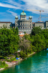 Wall Mural - BERN, SWITZERLAND - August 2nd 2022: The Federal Palace of Switzerland (Bundeshaus) and people enjoying river life to beat the summer heat.