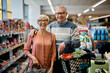 © Drazen - Portrait of happy senior couple in supermarket looking at camera.