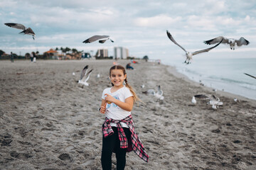 smiling girl on the beach feeding gulls 