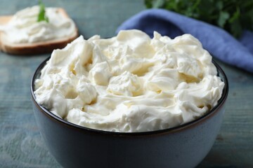 Tasty cream cheese on light blue wooden table, closeup