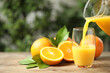 Pouring orange juice into glass at wooden table. Space for text