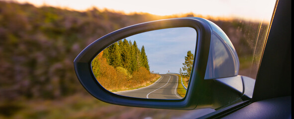 The view of the mountains in the car's rearview mirror.