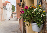 Fototapeta Do przedpokoju - white pot with colorful flowers hanging outside a house in Italy