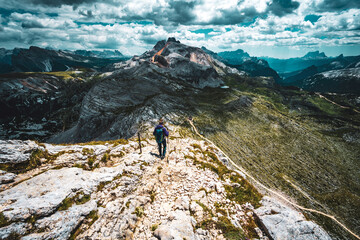 Young woman is hiking on beautiful trail Seekofel to Baires Lake in the Dolomite mountains in the afternoon. Seekofel , Dolomites, South Tirol, Italy, Europe.