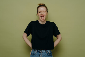 Silly brunette woman wearing casual clothes showing her tongue