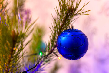 Wall Mural - The Christmas ball on a Christmas tree against the background of blurry lights from a garland. New Year's and Christmas.