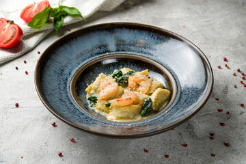 Wall Mural - ravioli with shrimp and spinach on blue plate on grey table