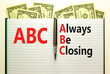ABC always be closing symbol. Concept words ABC always be closing on white note on a beautiful background from dollar bills. Metallic pen. Business and ABC always be closing concept. Copy space.