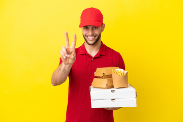 Wall Mural - pizza delivery man picking up pizza boxes and burgers over isolated background smiling and showing victory sign