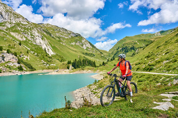 Wall Mural - active senior woman, riding her electric mountain bike at Spuller Lake in the Arlberg area near the famous village of Lech, Tirol, Austrian Alps