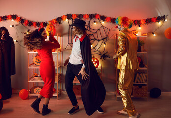 Wall Mural - Happy diverse people in costumes makeup dance celebrate Halloween in decorated home together. Smiling friends have fun on all saints eve party or masquerade. Fall party, celebration concept.