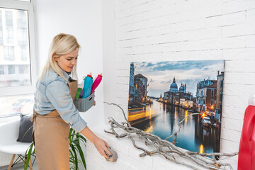 Wall Mural - Beautiful young woman makes cleaning the house. Girl rubs dust.