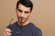 © SHOTPRIME STUDIO - portrait man in a gray T-shirt and glasses tin hands beige background
