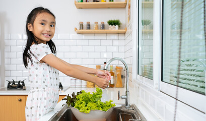 Little girl washing vegetable for Healthy Dinner. Importance of Washing Hands and Healthy Eating Habits. Cute Child Helping Her Beautiful Caring Parents.