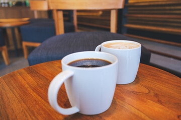 Wall Mural - Closeup image of two white cups of hot coffee on wooden table in cafe