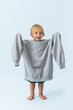 © zzzdim - Adorable happy little blond boy in overside hoodie lifting hands in sleeves