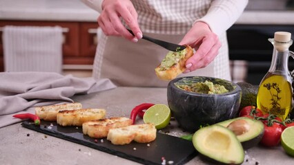 Wall Mural - woman making bruschetta with freshly made guacamole sauce at domestic kitchen