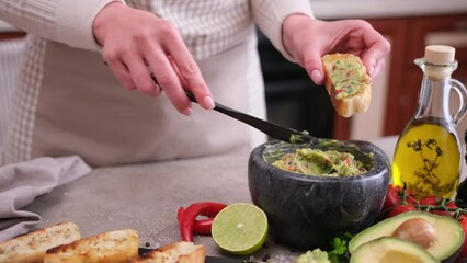 Wall Mural - woman making bruschetta with freshly made guacamole sauce at domestic kitchen